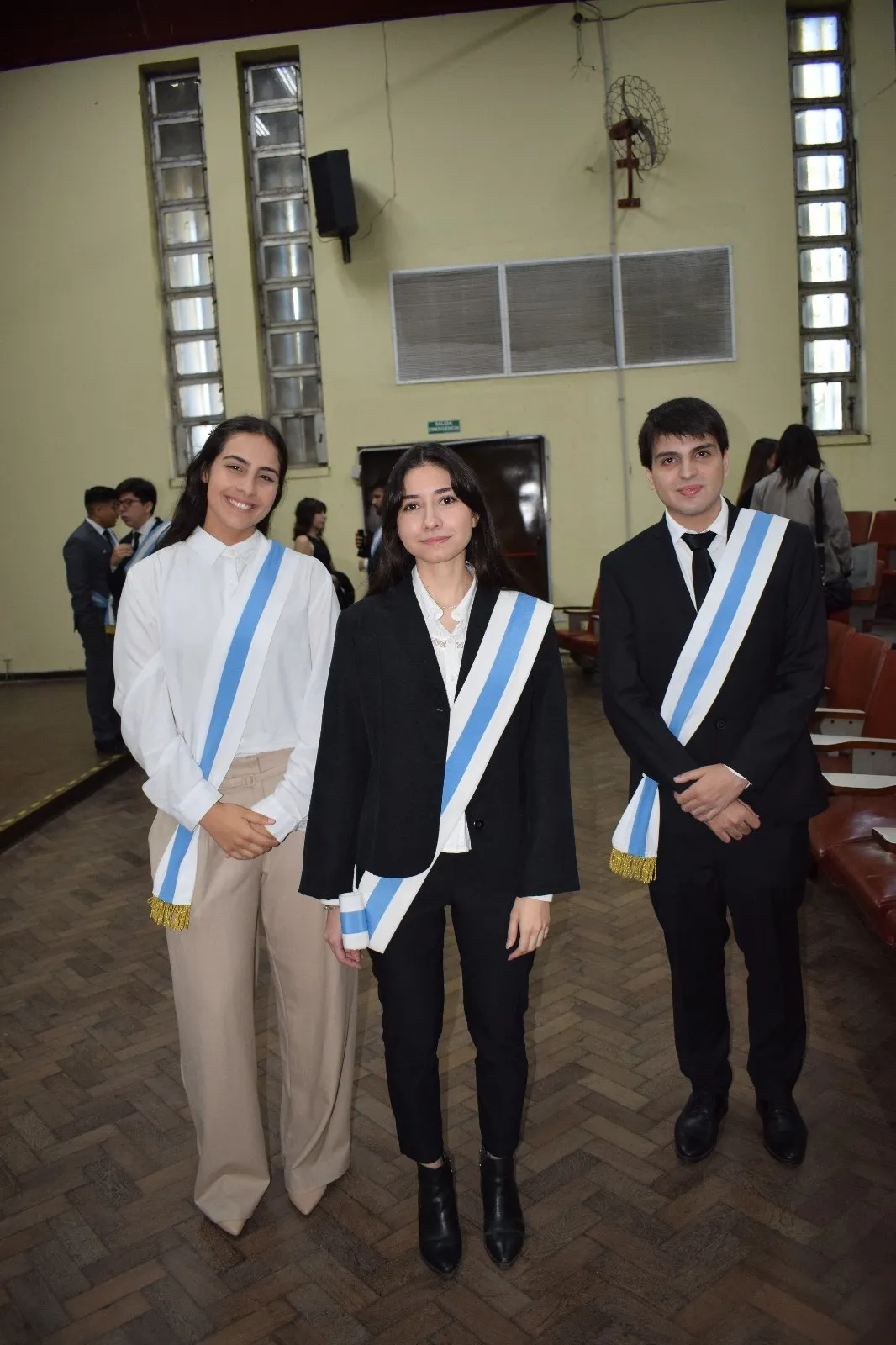 Luis Medina Raed avec deux autres escortes portant leurs écharpes, lors de la cérémonie de la FACET.