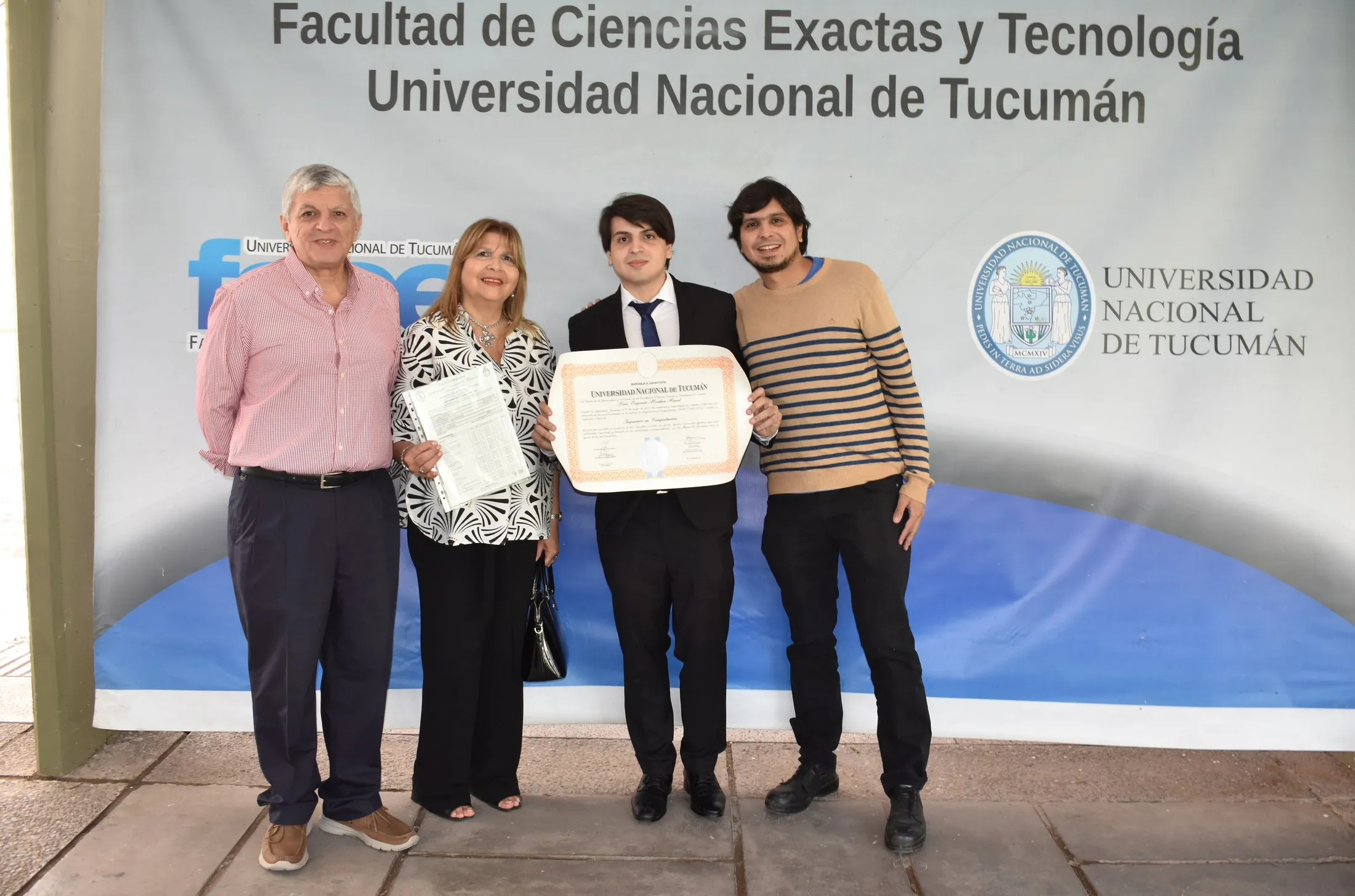 Luis Medina Raed con su familia y su título de Ingeniero en Computación, frente al banner de la Facultad de Ciencias Exactas y Tecnología (UNT).