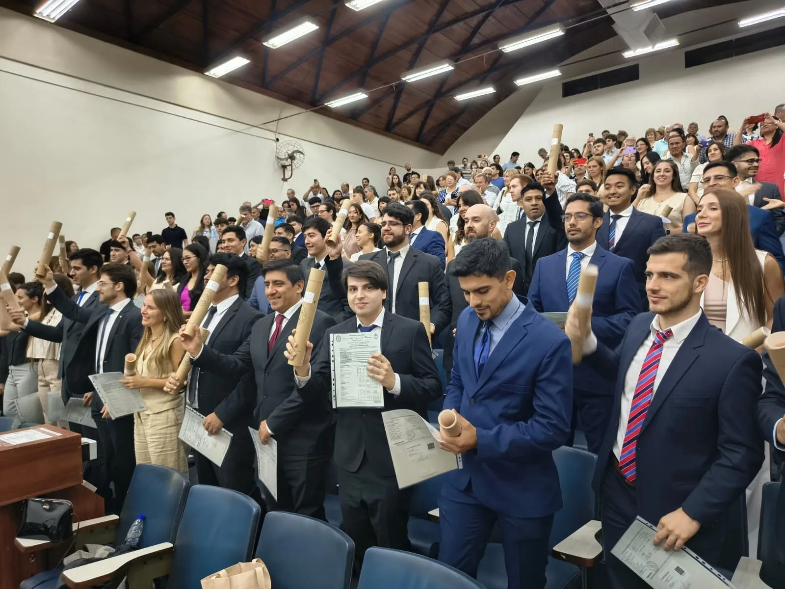 Egresados celebrando con sus diplomas en el aula magna durante la colación de grado de la FACET.